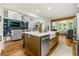 Bright kitchen features island, white cabinets, stainless appliances, hardwood floors and open layout to Gathering room at 6655 Manchester Pl, Cumming, GA 30040