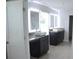 Modern bathroom with dual sinks, granite counters, tile floors, and backlit mirrors at 1612 Fuma Leaf Way, Mcdonough, GA 30253