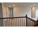 Second floor hallway with neutral carpeting and decorative iron railings at 1612 Fuma Leaf Way, Mcdonough, GA 30253