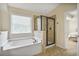A well-lit bathroom features a soaking tub, a separate glass enclosed shower, and tiled flooring at 11686 Davenport Ln, Alpharetta, GA 30005