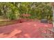 Large red deck with a hot tub, grill, seating area, and wooded views, ideal for outdoor gatherings at 3866 Teresa Sw Ter, Lilburn, GA 30047