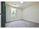 An empty bedroom with neutral colored walls and carpeting, along with a window to let in light at 5023 Rockborough Trl, Norcross, GA 30071