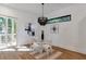 A modern dining room with chandelier, glass table, white chairs, and view to deck at 1464 Ezra Church Nw Dr, Atlanta, GA 30314