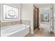 A luxurious bathroom features a soaking tub beneath a decorative window and a glass-enclosed shower at 2330 Cheatham Creek Ct, Cumming, GA 30040
