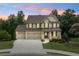 Charming two-story brick home with a three-car garage and landscaped front yard at sunset at 2330 Cheatham Creek Ct, Cumming, GA 30040