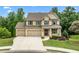 Charming two-story brick home with a three-car garage and landscaped front yard in daylight at 2330 Cheatham Creek Ct, Cumming, GA 30040