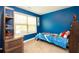 Blue bedroom featuring a bed with dinosaur bedding, a window and wood shelving unit at 4560 Buckskin Way, Douglasville, GA 30135