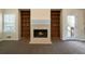 Living room featuring a cozy fireplace flanked by built-in bookshelves and a window for natural light at 120 Paces Lakes Pt, Dallas, GA 30157