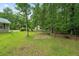 Backyard with grassy area, mature trees, and a fire pit area at 1267 Austin Bridge Rd, Douglasville, GA 30134