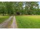 Gravel driveway leading to a lush, green front yard with mature trees at 1267 Austin Bridge Rd, Douglasville, GA 30134