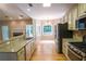 Open concept kitchen features stainless appliances, granite counters, light wood floors, and seamlessly connects with the living area at 19 Thimblemill Ct, Villa Rica, GA 30180