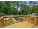 Pool deck with a wooden railing overlooking an inground pool surrounded by a wooded area and a fence at 35 Lady Morgan Ln, Dallas, GA 30157