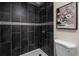 Modern shower with black tile and decorative band, paired with a white toilet and floral art at 35 Lady Morgan Ln, Dallas, GA 30157