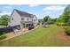 Wide backyard view showcasing a covered patio, fire pit area, playset, and manicured lawn at 121 Bradshaw Park Dr, Woodstock, GA 30188