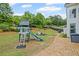 Large backyard featuring a play set, fire pit area, wooded perimeter, and gravel path at 121 Bradshaw Park Dr, Woodstock, GA 30188