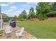 Large backyard with green grass, patio area, grilling station, and wooded area beyond at 121 Bradshaw Park Dr, Woodstock, GA 30188