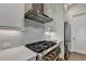 Close up of a professional range and oven, stainless vent hood and white cabinets at 1002 Harvest Park Ln, Suwanee, GA 30024