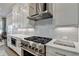 Well-equipped kitchen with stainless steel stove and hood, white cabinets, and light countertops at 1002 Harvest Park Ln, Suwanee, GA 30024