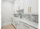 Laundry area features white cabinets, gold hardware, a farmhouse sink, and marble countertops and backsplash at 4539 Braselton Hwy, Hoschton, GA 30548