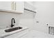 Bright laundry room boasts marble counters, modern faucet, and white cabinets offering ample storage at 4539 Braselton Hwy, Hoschton, GA 30548