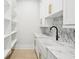 Bright laundry room features white cabinets, open shelving, a farmhouse sink, and marble countertops at 4539 Braselton Hwy, Hoschton, GA 30548
