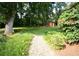 Landscaped backyard with a large lawn, mature trees, and a small shed in the distance at 5152 Suggs St, Powder Springs, GA 30127