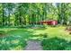 Spacious backyard featuring lush greenery, mature trees, and a red storage shed at 5152 Suggs St, Powder Springs, GA 30127