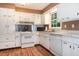 Traditional kitchen featuring white cabinets, appliances, and wood flooring at 5152 Suggs St, Powder Springs, GA 30127