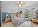 Stylish bedroom featuring a wood accent wall, ceiling fan, and bright natural light at 200 Whispering Pines Dr, Woodstock, GA 30188