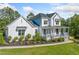 Elegant white home with a charming front porch and lush green lawn on a sunny day at 200 Whispering Pines Dr, Woodstock, GA 30188