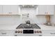 Close up of kitchen featuring a modern gas range, stylish backsplash, and white cabinetry at 200 Whispering Pines Dr, Woodstock, GA 30188