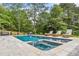 Sparkling swimming pool and spa with lounge chairs on the patio and mature trees in the background at 200 Whispering Pines Dr, Woodstock, GA 30188
