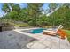 Backyard swimming pool with lounge chairs on a stone paver patio and privacy fence in the background at 200 Whispering Pines Dr, Woodstock, GA 30188