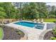 Swimming pool and spa surrounded by stone paver patio with a landscaped yard at 200 Whispering Pines Dr, Woodstock, GA 30188