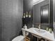 Chic powder room featuring textured wallpaper, modern fixtures, and sleek design elements at 200 Whispering Pines Dr, Woodstock, GA 30188