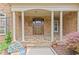 Inviting front porch featuring stone columns, a decorative front door, and manicured landscaping at 2430 Hemrick Rd, Cumming, GA 30041