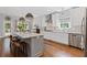 Open kitchen with white cabinets, stainless steel appliances, island with seating, and hardwood floors at 2430 Hemrick Rd, Cumming, GA 30041