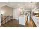 Open-concept kitchen flows seamlessly from the staircase, featuring a central island, white cabinets, and modern pendant lighting at 6613 Encore Blvd, Atlanta, GA 30328