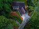 An aerial view displays the home with its long driveway and surrounding wooded area at 7250 Hunters Branch Dr, Atlanta, GA 30328