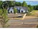 Modern white farmhouse exterior with dark roof, manicured landscaping, and ample parking at 117 Oliver Dr, Locust Grove, GA 30248