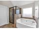 Well-lit bathroom featuring a soaking tub and a glass-enclosed shower, complete with a tile surround at 845 Nevis Way, Mcdonough, GA 30253