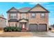 Two story brick home with a red front door, mature landscaping and a two-car garage at 845 Nevis Way, Mcdonough, GA 30253