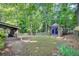 Secluded backyard featuring mature trees, a garden shed with charming purple doors, and a screened-in porch at 235 Trailmore Ct, Roswell, GA 30076