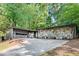 Contemporary home with a stone facade, attached garage, and long driveway nestled among mature trees at 235 Trailmore Ct, Roswell, GA 30076