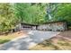 Contemporary home with stone details, and a spacious driveway surrounded by lush greenery at 235 Trailmore Ct, Roswell, GA 30076