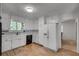 Well lit kitchen with white cabinetry, black appliances, tile countertops and wood-look flooring at 235 Trailmore Ct, Roswell, GA 30076