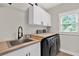 This laundry room features white cabinetry, a stainless steel sink, and a modern washer and dryer at 201 Beacon Cv, Canton, GA 30114