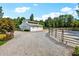 Driveway leading to a white barn with mature trees, gravel, and a riding arena at 206 Savanna Estates Ct, Canton, GA 30115