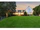 Elegant white home with manicured lawn and lush landscaping, exudes curb appeal and timeless charm at dusk at 206 Savanna Estates Ct, Canton, GA 30115