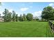 Vast green front yard with a distant view of a well-maintained house and black wooden fence at 206 Savanna Estates Ct, Canton, GA 30115